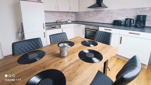 Une cuisine moderne avec des meubles blancs, une hotte noire et une table à manger décorée de disques vinyles noirs.