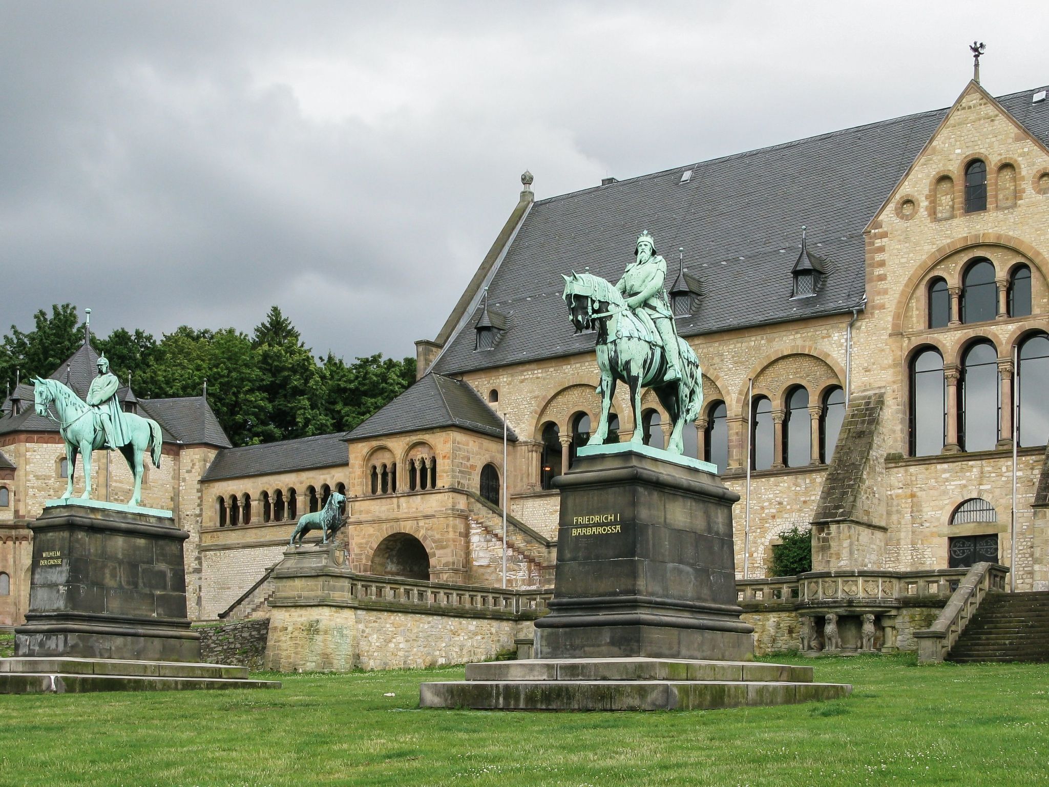 Un edificio histórico con estatuas de figuras a caballo y una estatua de una figura sentada sobre un pedestal.