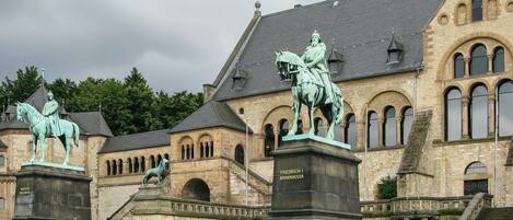 Un edificio histórico con estatuas de figuras a caballo y una estatua de una figura sentada sobre un pedestal.