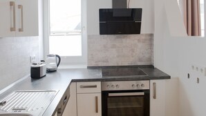 A modern kitchen with a built-in oven, a stovetop, and a window providing natural light. - in Goslar mit Terrasse und Grill by Interhome (Goslar)