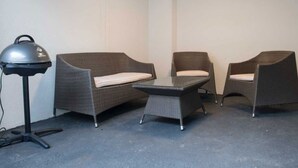A room with two wicker chairs, a small table, and a floor lamp. - in Goslar mit Terrasse und Grill by Interhome (Goslar)