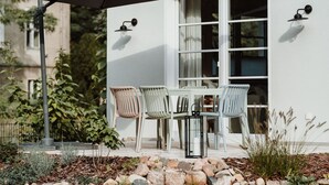 Un patio al aire libre con una mesa, sillas, un paraguas grande y un aplique de pared.