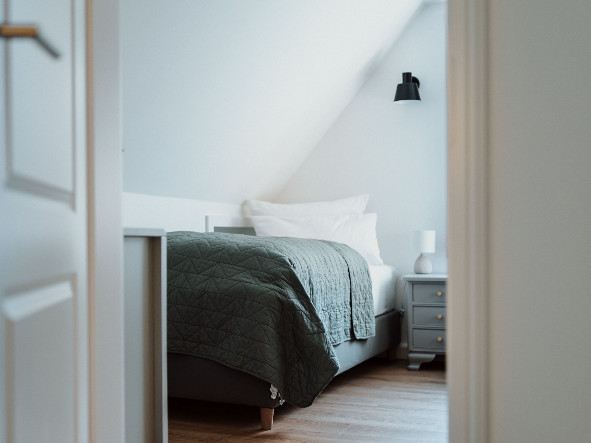 A bedroom with a bed, a bedside table, and a nightstand.