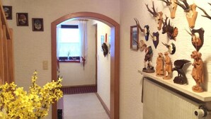 Ein Flur mit Heizkörper, einem fenster mit Vorhängen und einer Wanddekoration aus montierten Tierköpfen und Figuren.