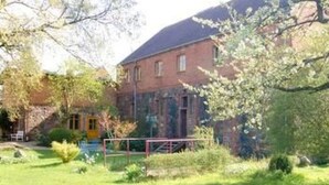 Een gebouw van rode bakstenen met een tuin ervoor.