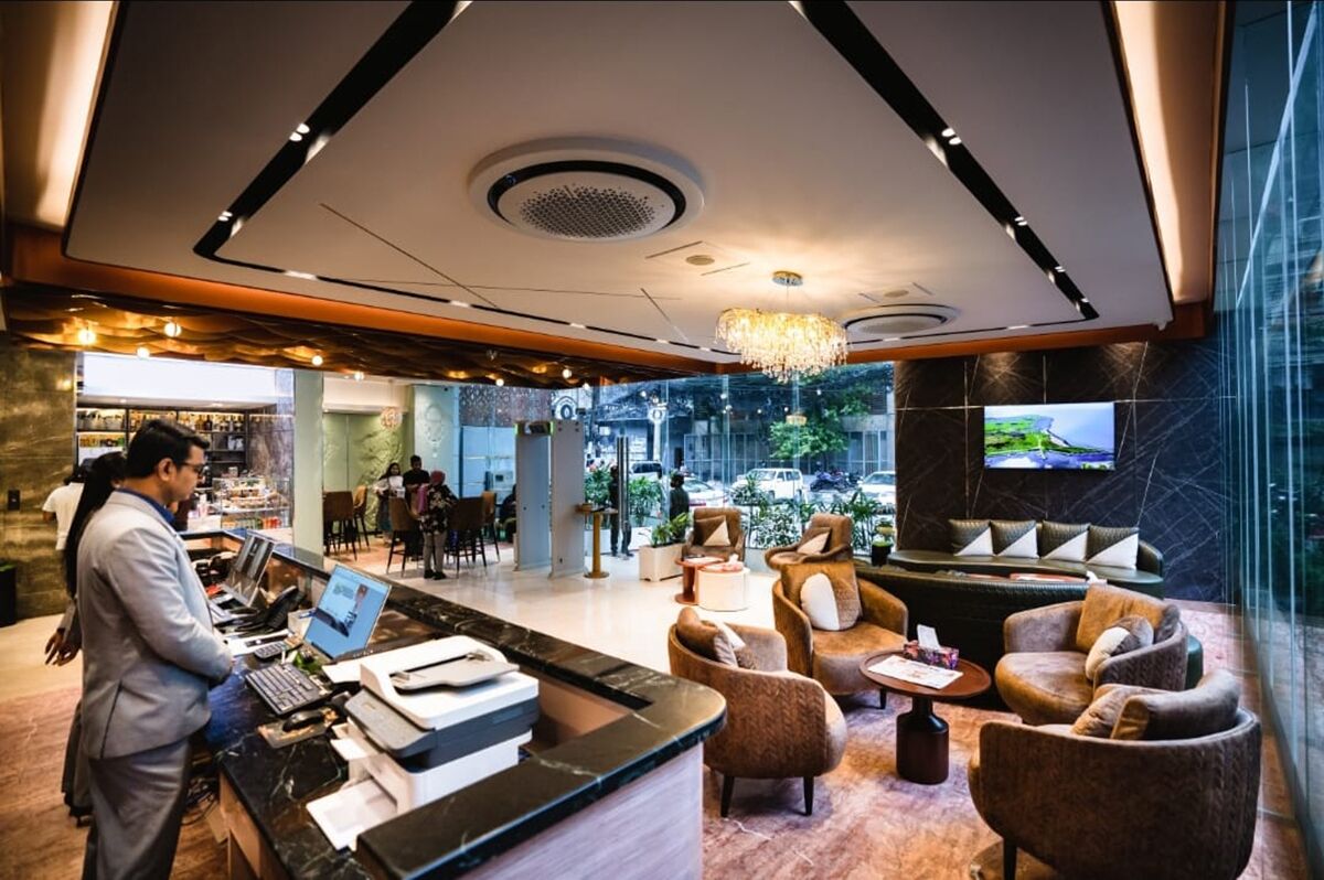 A hotel lobby with a reception desk, seating area, and a large TV screen.