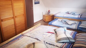 Camera da letto con due letti, un armadio in legno e un comodino con una lampada.