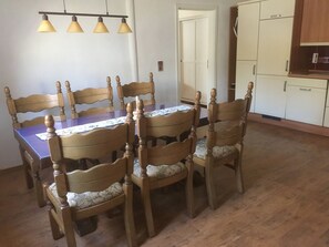 A dining area with a wooden table and chairs, a chandelier, and a kitchen in the background. - Parkblick in Ziethen by Interhome (Ziethen)