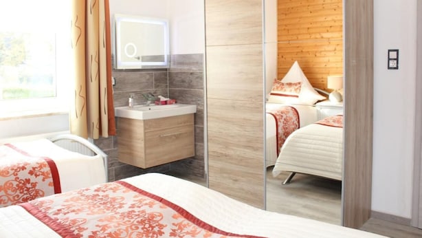 Un dormitorio moderno con un armario de madera, una mesita de noche, un espejo y una ventana con cortinas.
