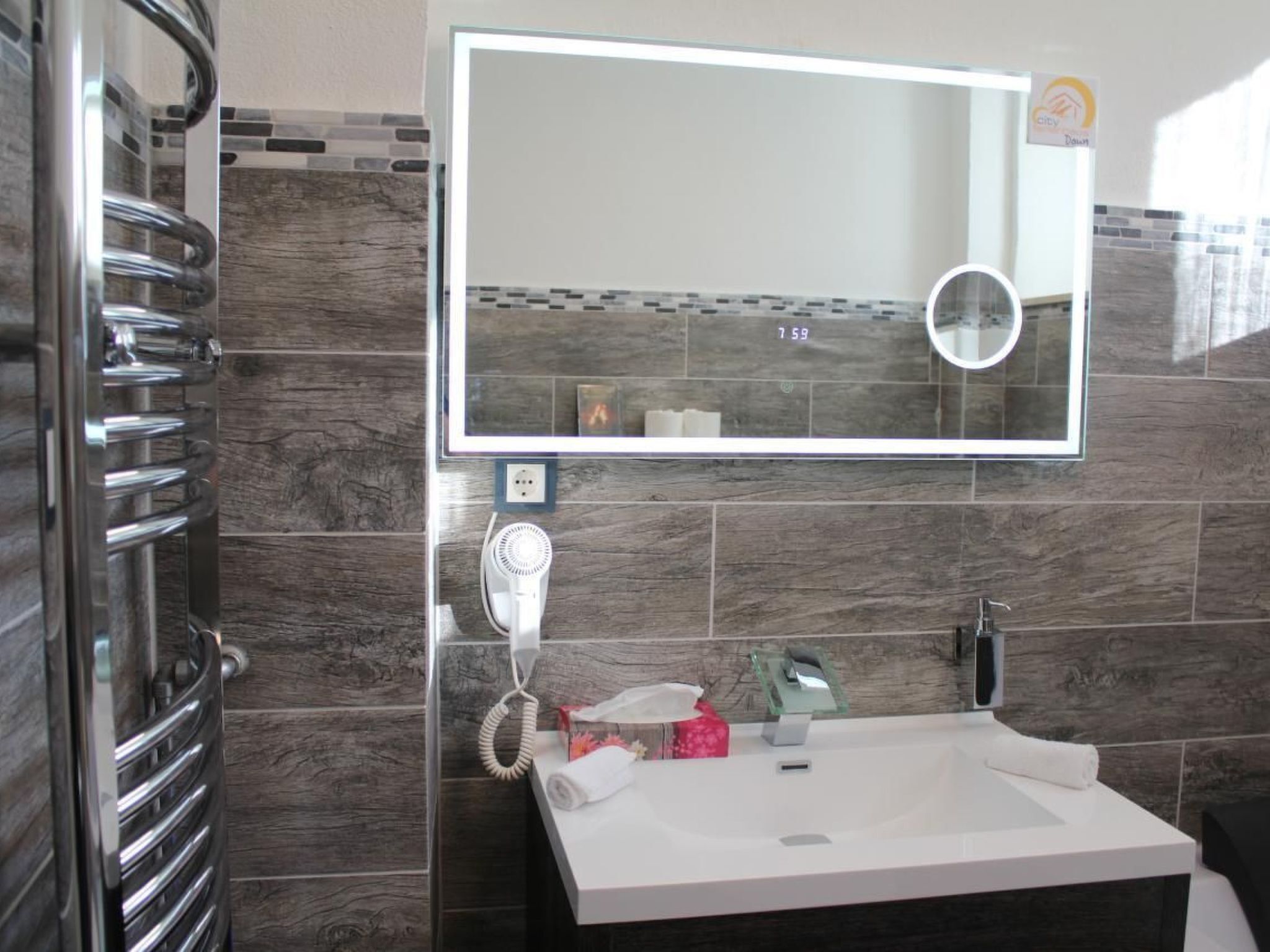A bathroom with a large mirror, a towel rack, a hairdryer, and a sink.