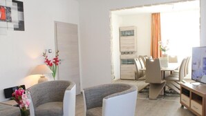 Una sala de estar moderna con un sofá, sillones, una mesa de centro y un comedor con sillas y una mesa.
