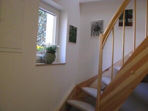 Eine Treppe mit hölzernen Geländern und einem kleinen Fenster mit einem Blumentopf.