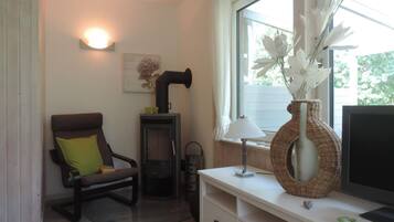 Een gezellige woonkamer met een open haard, een comfortabele fauteuil, een witte console tafel en een raam met uitzicht op groen.