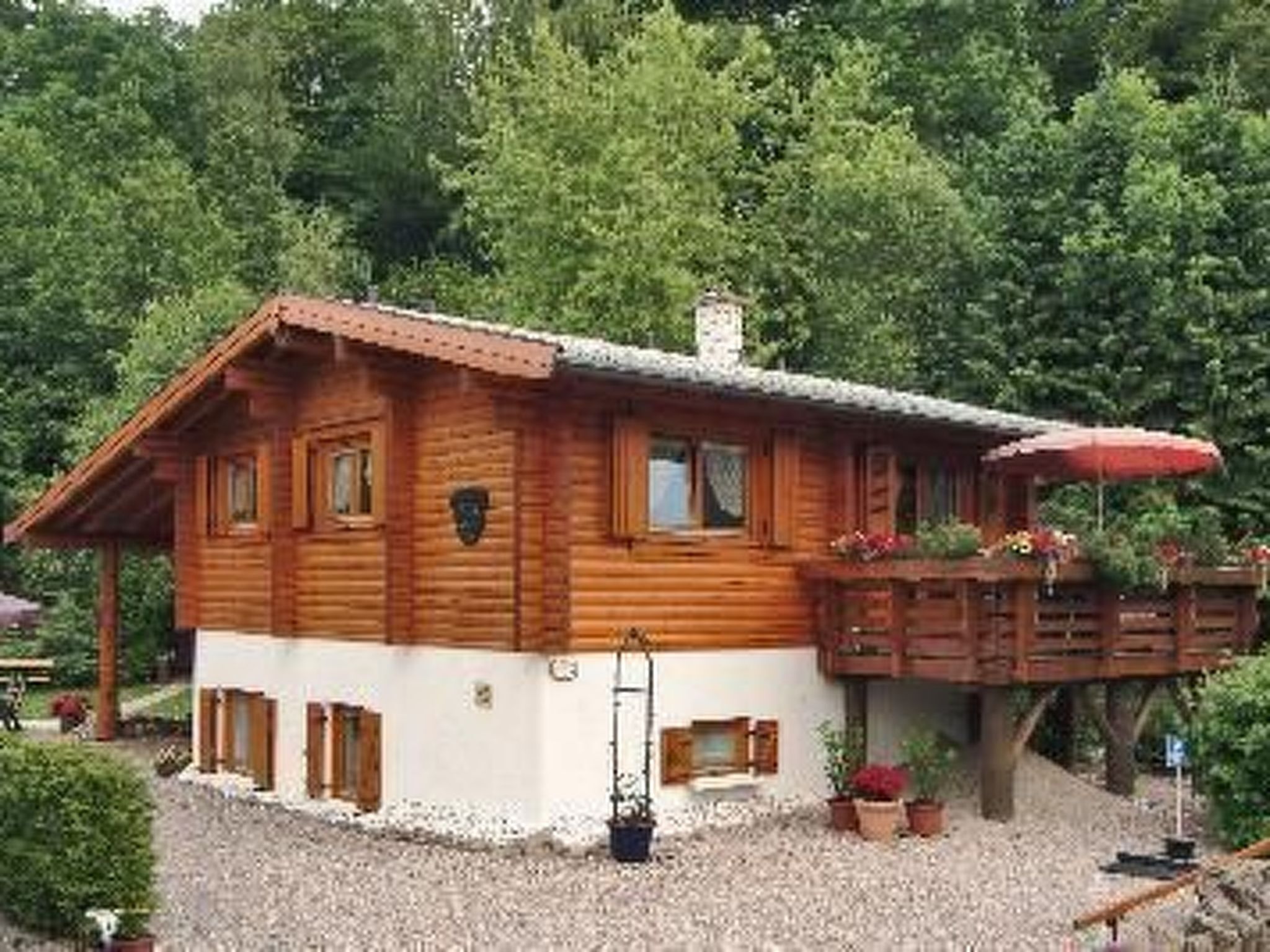 Une cabane en bois dotée d’un balcon, entourée d’arbres.