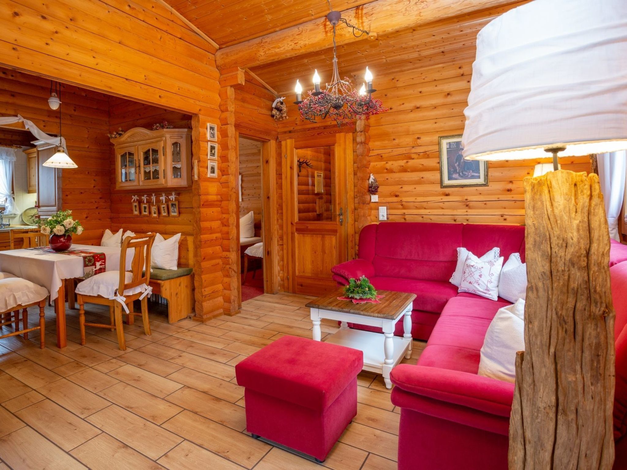 Ein gemütliches Blockhaus-Interieur mit einem roten Sofa, einem Holzespeisesaal und einem Kronleuchter.