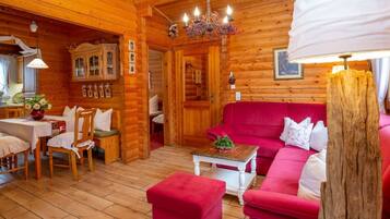 Ein gemütliches Blockhaus-Interieur mit einem roten Sofa, einem Holzespeisesaal und einem Kronleuchter.