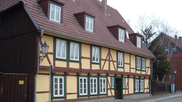 Un bâtiment traditionnel à colombages, doté de nombreuses fenêtres et d’une cheminée.