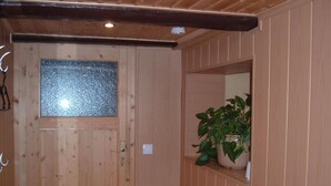 Une porte en bois avec un vitrage dépoli, une plante en pot posée sur une étagère et un interrupteur.
