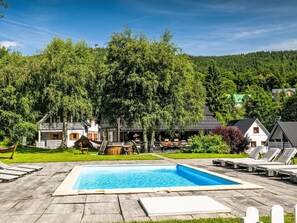 A swimming pool with lounge chairs, a wooden deck, and a view of houses and trees. - Landhaus mit gemeinschaftlichem Pool by Interhome (Szklarska Poreba)
