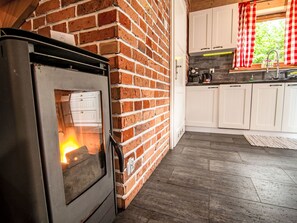 A kitchen with a brick wall, a stove, white cabinets, and a window with red curtains. - Landhaus mit gemeinschaftlichem Pool by Interhome (Szklarska Poreba)