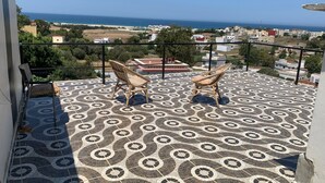 A balcony with patterned floor tiles, two wicker chairs, and a view of the sea and buildings. - Wohnung Panoramablick by Interhome (Tanger)