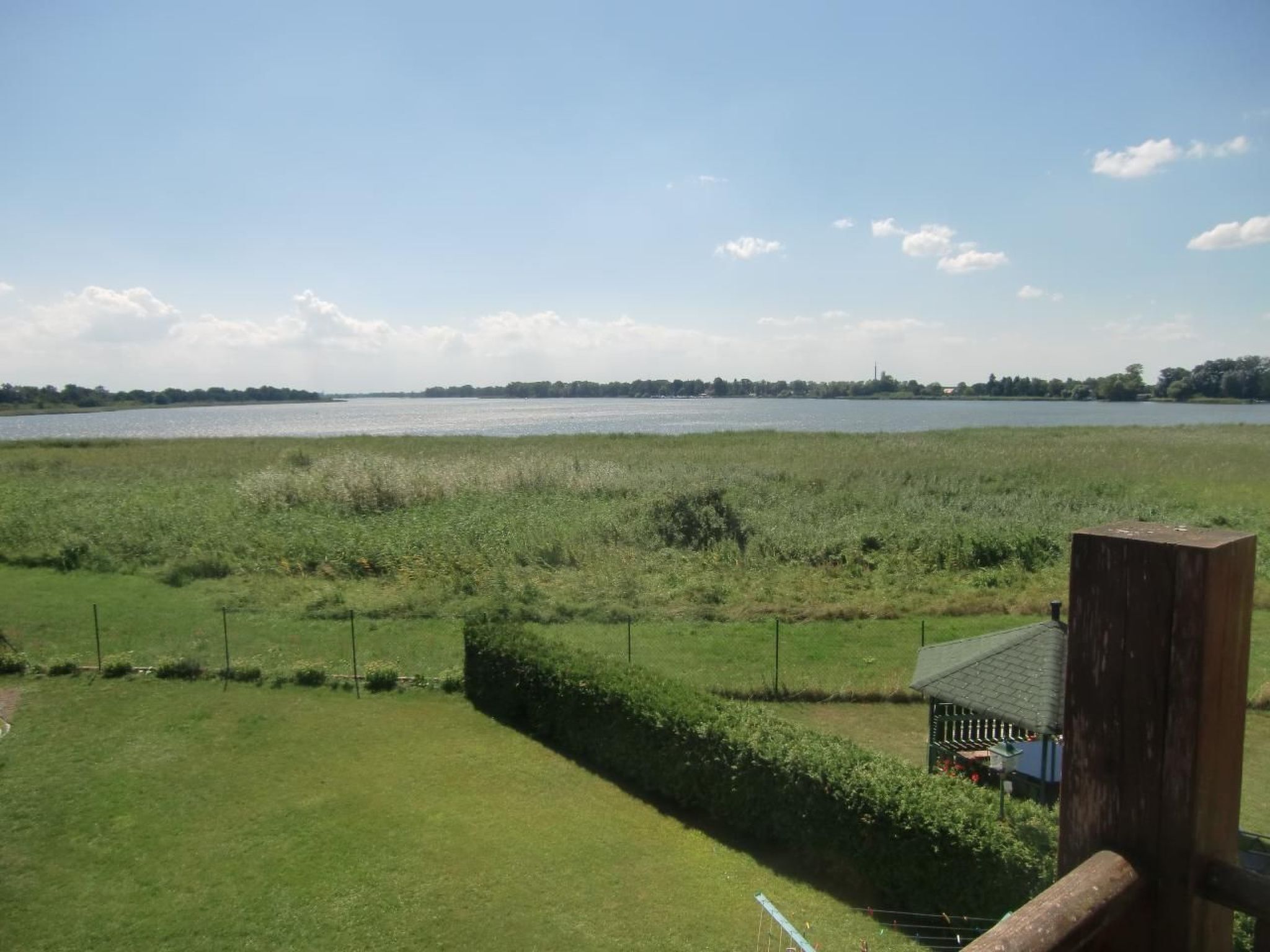 Een grasveld met een waterpartij op de achtergrond en een klein gebouw met een schuin dak.