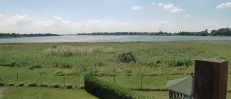 Een grasveld met een waterpartij op de achtergrond en een klein gebouw met een schuin dak.