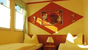 A hotel room with two beds, a nightstand, a lamp, and a painting of a rose on the wall. - mit Pool by Interhome (Beetzsee)