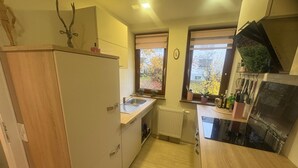 Een kleine keuken met een ingebouwde oven, een spoelbak en een raam met uitzicht op bomen.