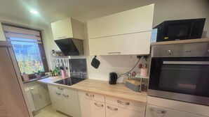 Een moderne keuken met roestvrijstalen apparatuur, houten aanrecht en een raam met uitzicht op groen.