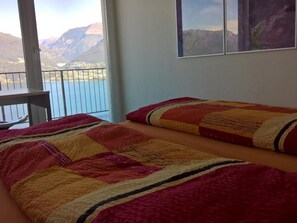 A bedroom with a bed, a window with a mountain view, and a balcony. - Wohnung an Traumlage mit Tessinerflair by Interhome (Vira)