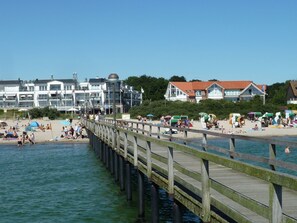 A pier extending into the water with a beach and buildings in the background. - Penthouse-Ostseepanorama by Interhome (Neustadt in Holstein)
