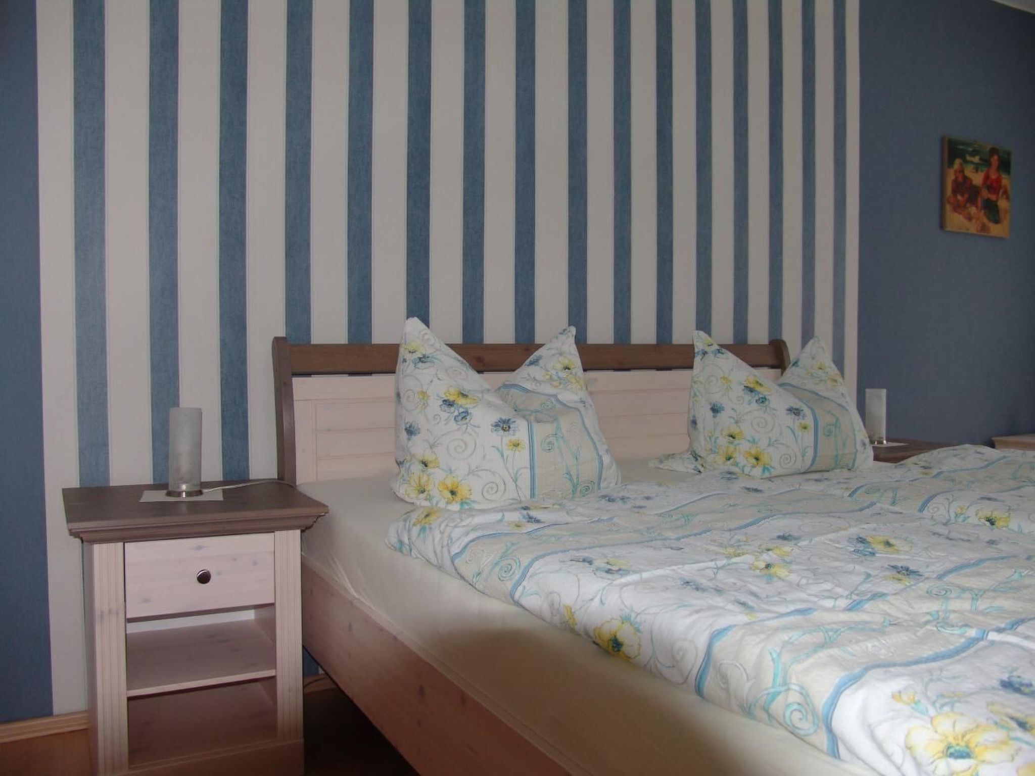 A bedroom with a bed, pillows, a bedside table, and a nightstand.