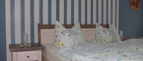 A bedroom with a bed, pillows, a bedside table, and a nightstand.