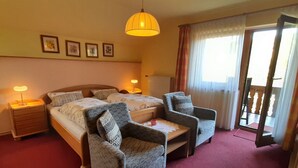 A hotel room with two beds, a sitting area with chairs, a desk, and a balcony with curtains. - in Bayerisch Eisenstein mit Garten by Interhome (Bayerisch Eisenstein)