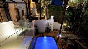 Un espace piscine extérieur moderne, doté d’une balustrade en verre et d’une terrasse en bois.
