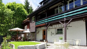 Une terrasse avec un sol en pierre, du mobilier d’extérieur et un petit espace aménagé en jardin.