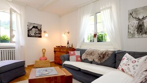 Un salon chaleureux avec un canapé, une table basse en bois et une fenêtre avec des rideaux.