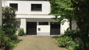 A two-story house with a paved driveway and a garden with various plants and flowers. - Eifelhaus4you by Interhome (Schleiden)