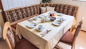 Un comedor con una mesa dispuesta para cuatro personas, rodeada por un banco con cojines estampados.