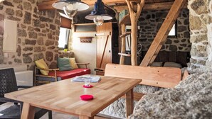 A rustic interior with stone walls, wooden beams, a wooden table, and a bench. - in idyllischer Lage im Süden Korsikas * by Interhome (Serra-di-Ferro)