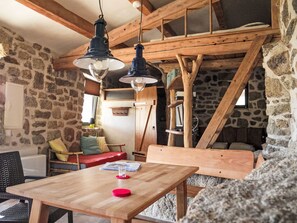 Un interior rústico con paredes de piedra, vigas de madera, una mesa de madera y un banco.