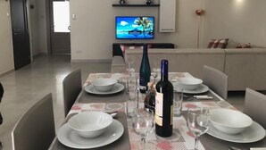 A dining area with a table set for four, a television in the background, and a sofa in the living area. - 3. Appartement mit Meerblick in Strandnähe by Interhome (Marsascala)