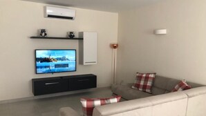 A modern living room with a flat-screen TV, a sofa, and a coffee table. - 3. Appartement mit Meerblick in Strandnähe by Interhome (Marsascala)