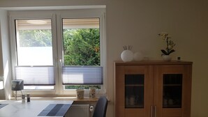 A dining area with a table, chairs, a cabinet, and a window with blinds. - Urlaub und zu Hause by Interhome (Naundorf)