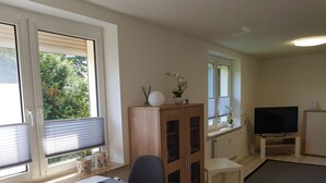 A compact living space with a dining area, a TV, and a cabinet with glass doors. - Urlaub und zu Hause by Interhome (Naundorf)