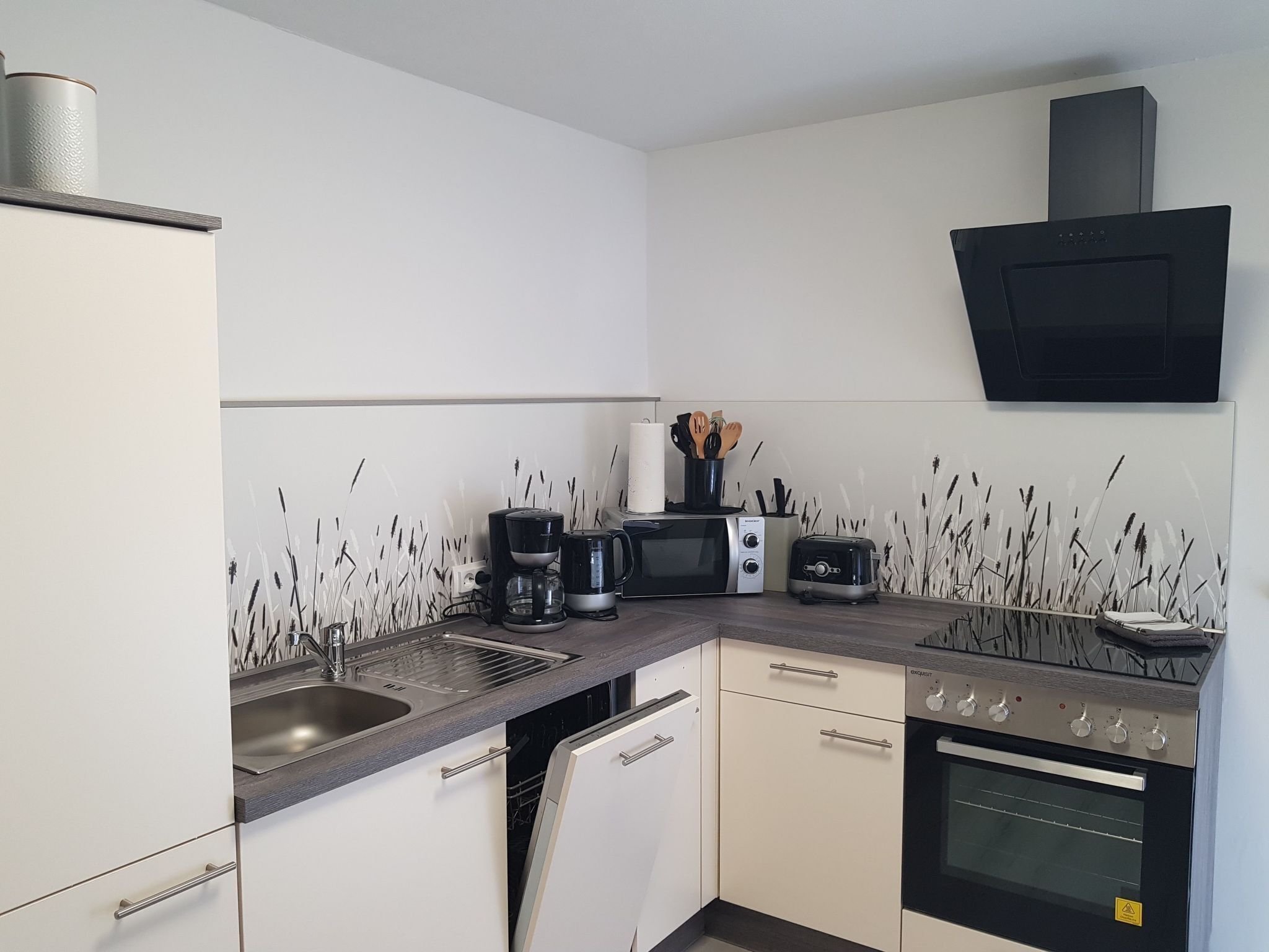 A compact kitchen with a sink, a coffee maker, a microwave, a toaster, and an oven.