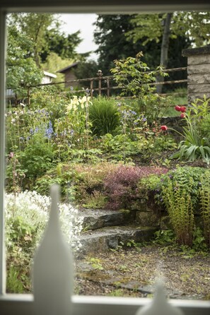 A garden with a variety of plants and flowers, a stone wall, and a wooden fence. - Wohlfühloase für Natur- und Gartenliebhaber by Interhome (Walkenried)