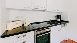 Eine moderne Küche mit weißen Schränken, einer schwarzen Arbeitsplatte, einem Toaster, einem Wasserkocher, einer Kaffeemaschine und einem Backofen.