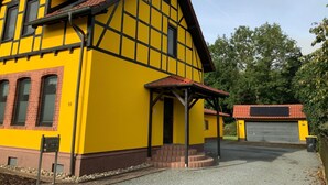 Ein gelbes Gebäude mit rotem Dach, Garage und einem Kiesweg.